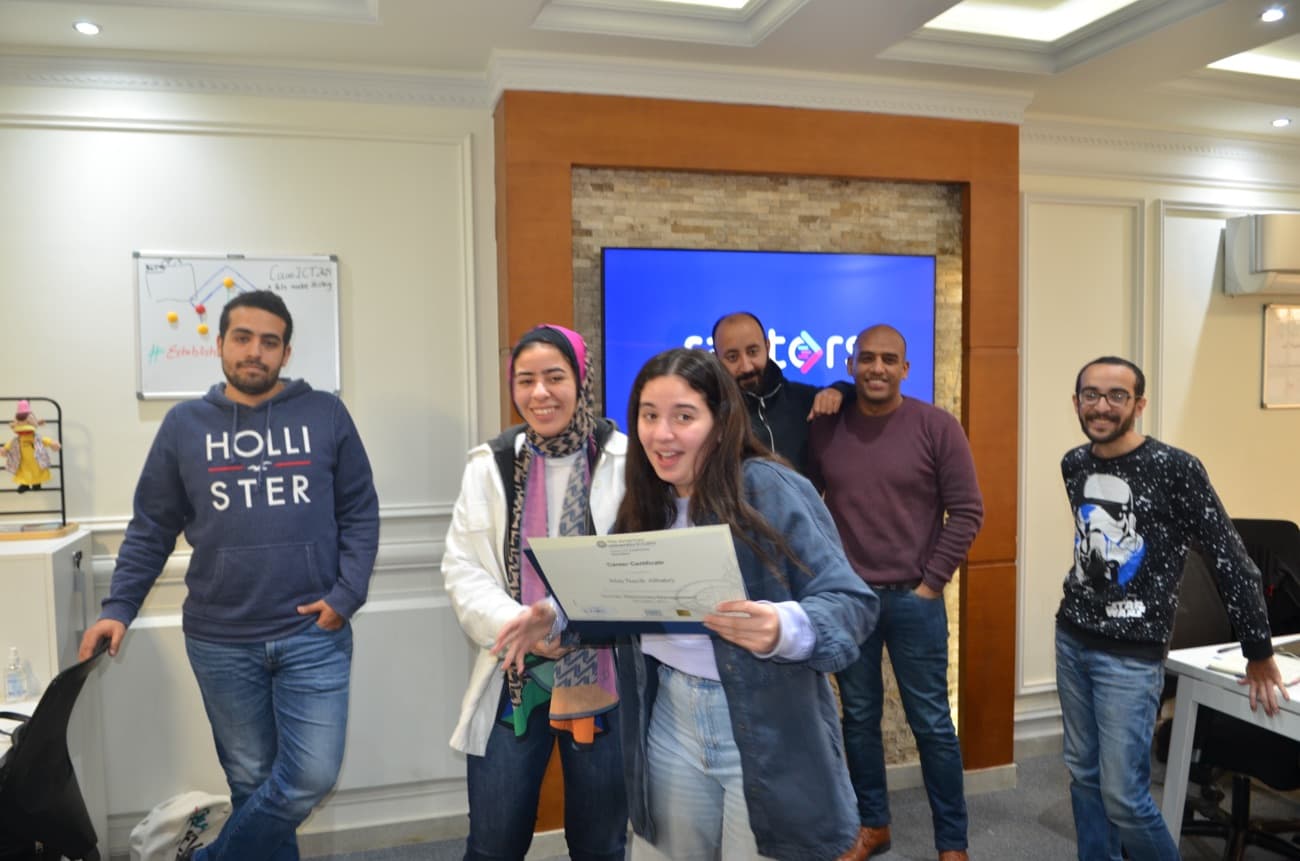 The team celebrating a certificate around the brand screen.